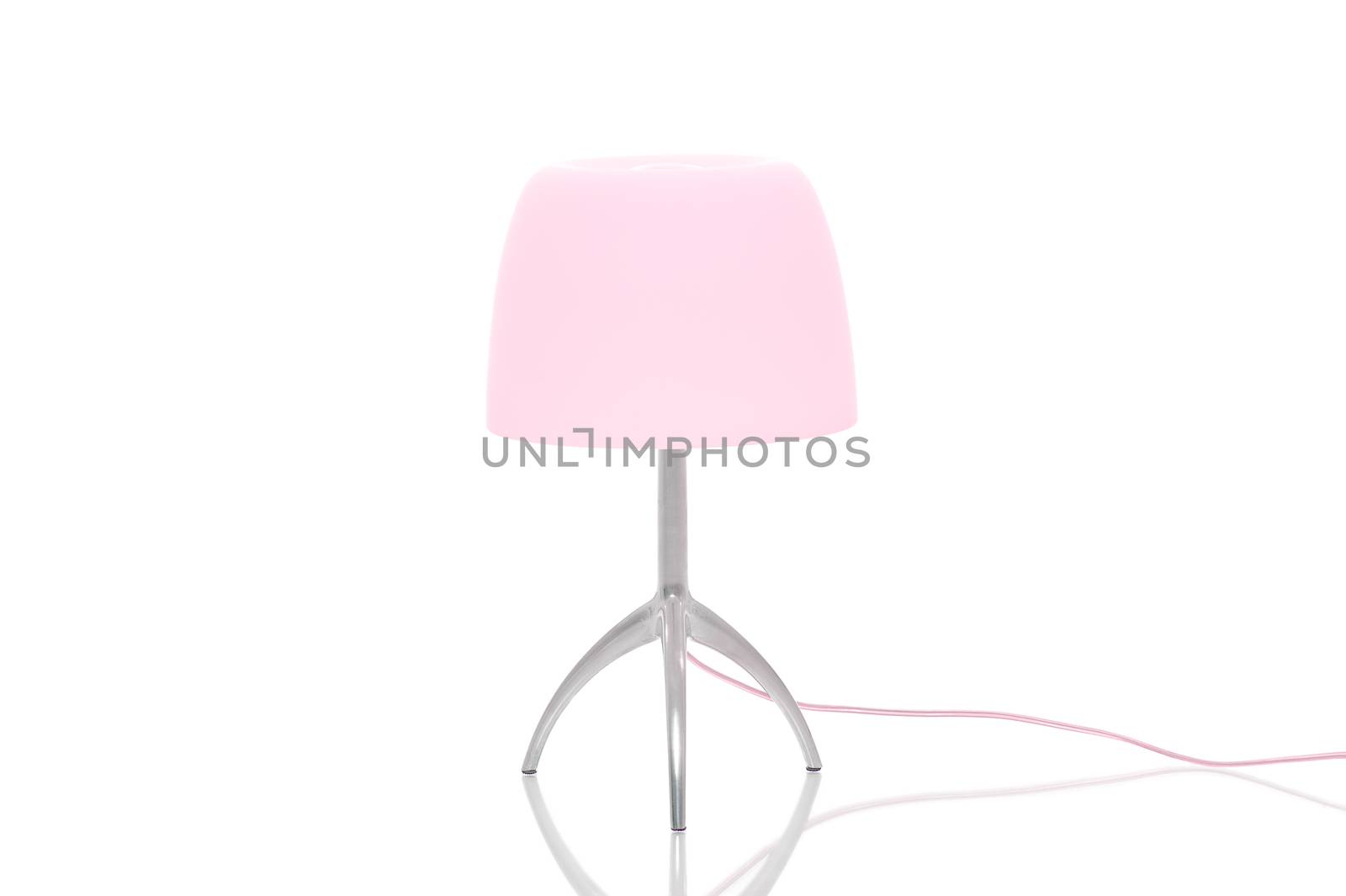 Elegant metal lamp with tripod legs and a pink lampshade standing on a reflective white surface with copyspace