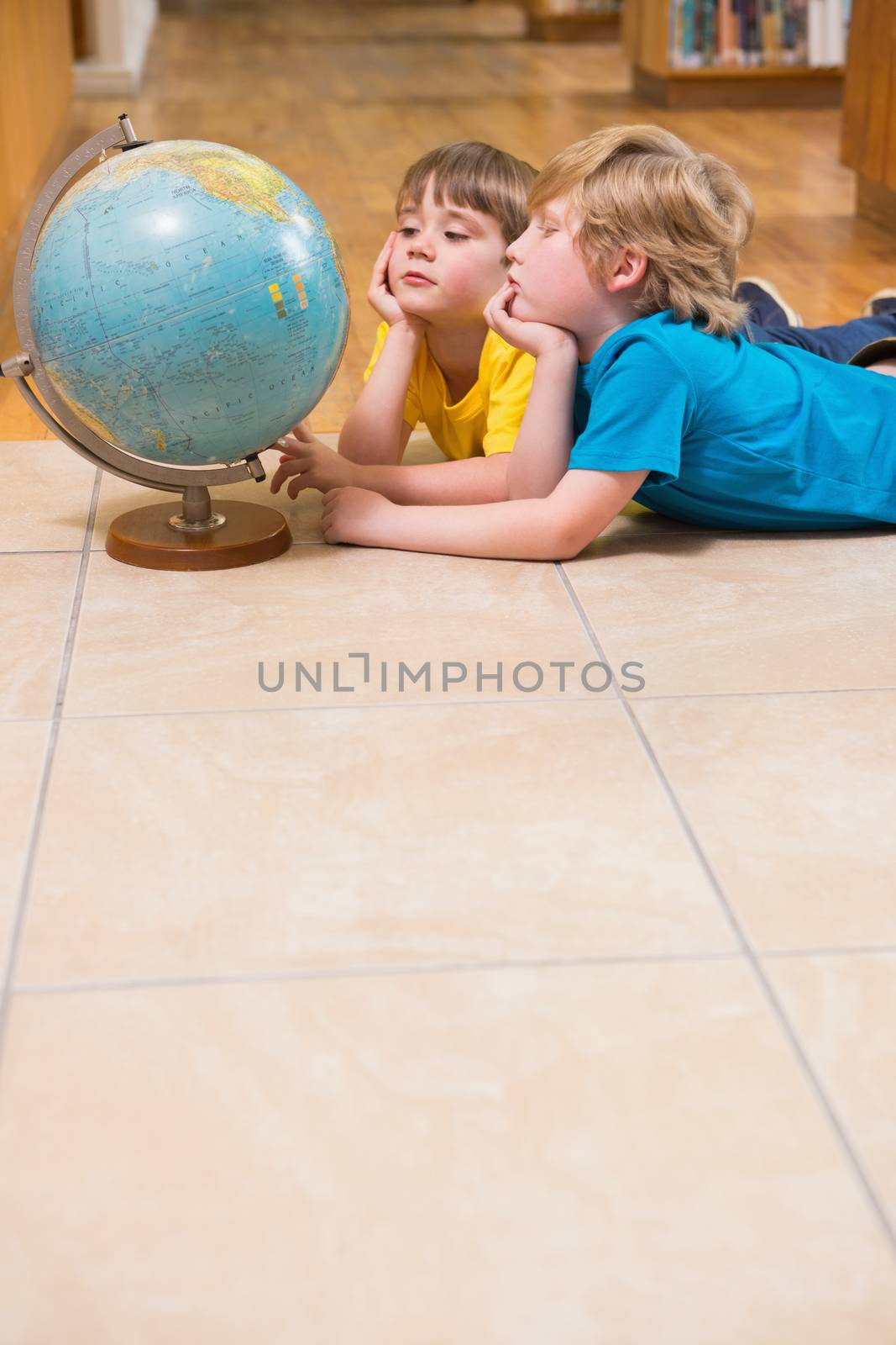 Cute pupils looking at globe at elementary school 