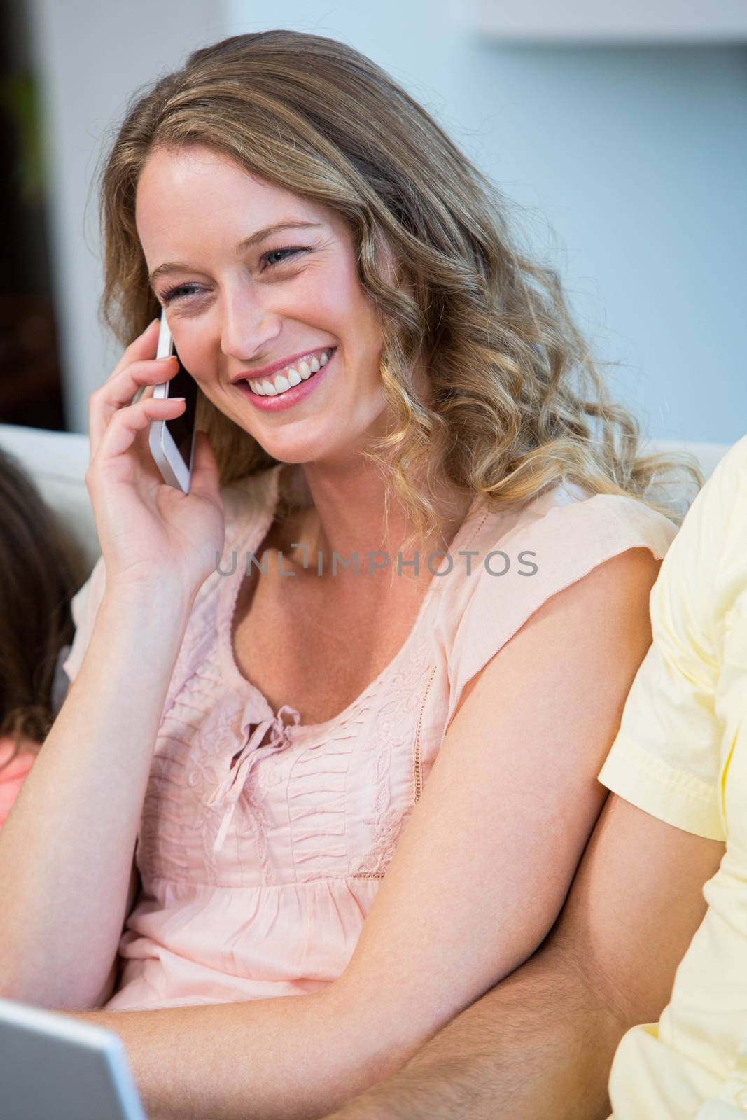 Happy mother on the phone on the couch at home in the living room