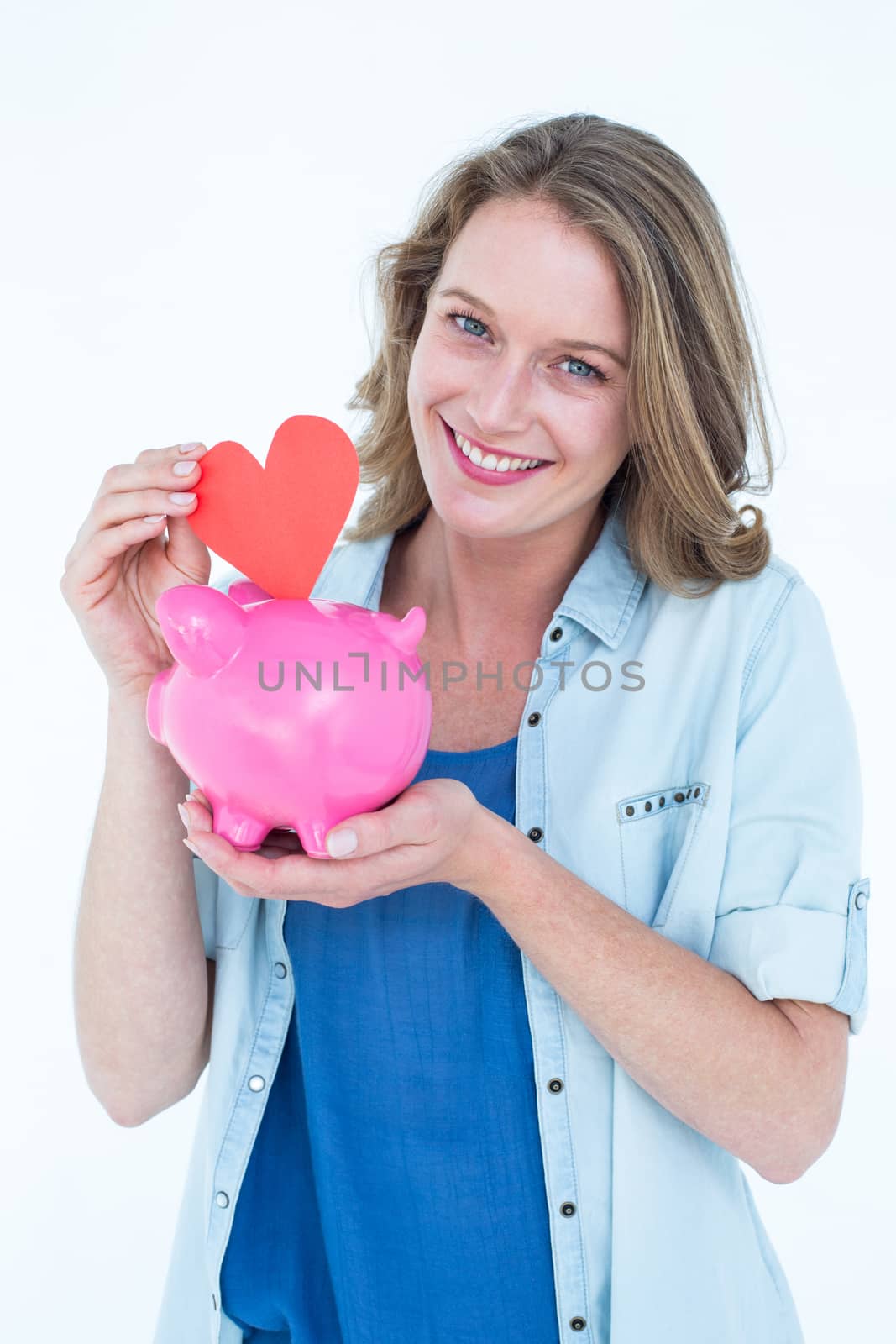 Smiling woman holding piggy bank and red heart  by Wavebreakmedia