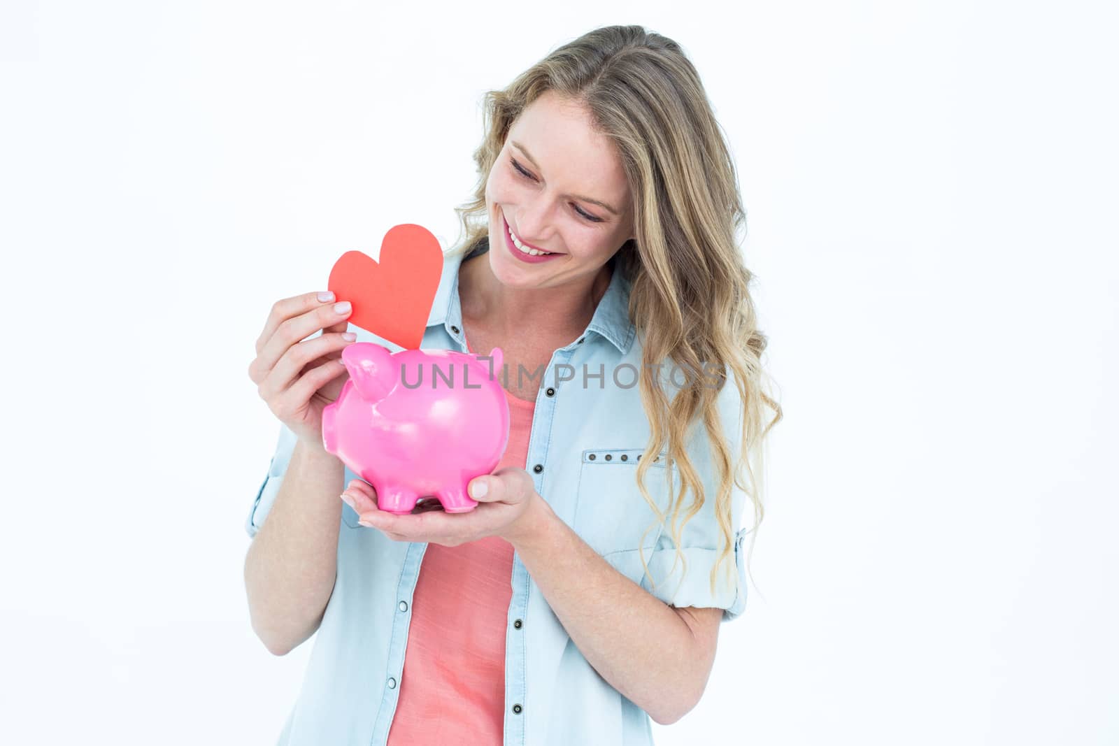 Smiling woman holding piggy bank and red heart  by Wavebreakmedia