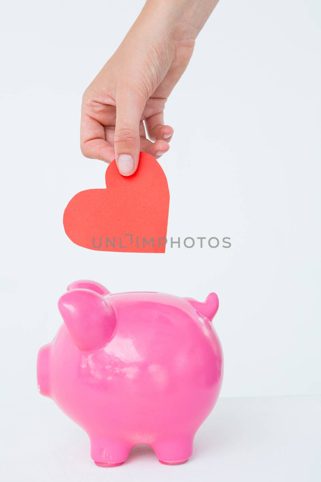 Woman holding piggy bank and red heart  by Wavebreakmedia