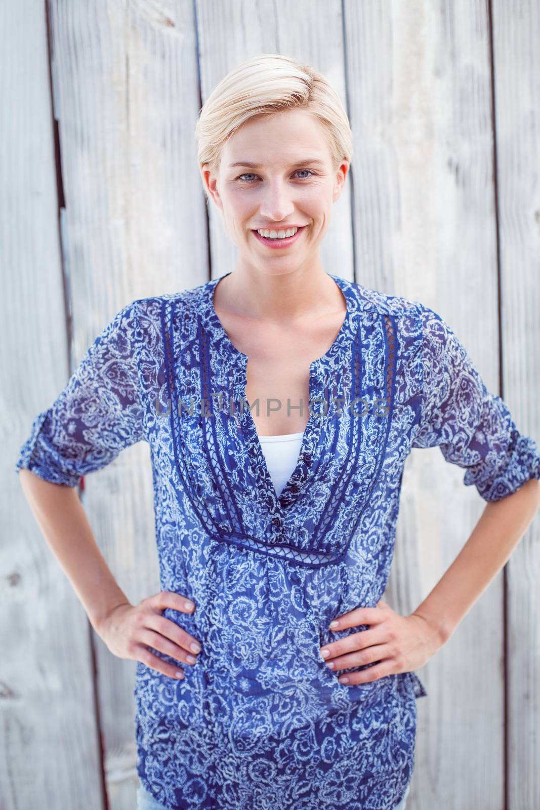 Pretty blonde woman standing hands on hips by Wavebreakmedia