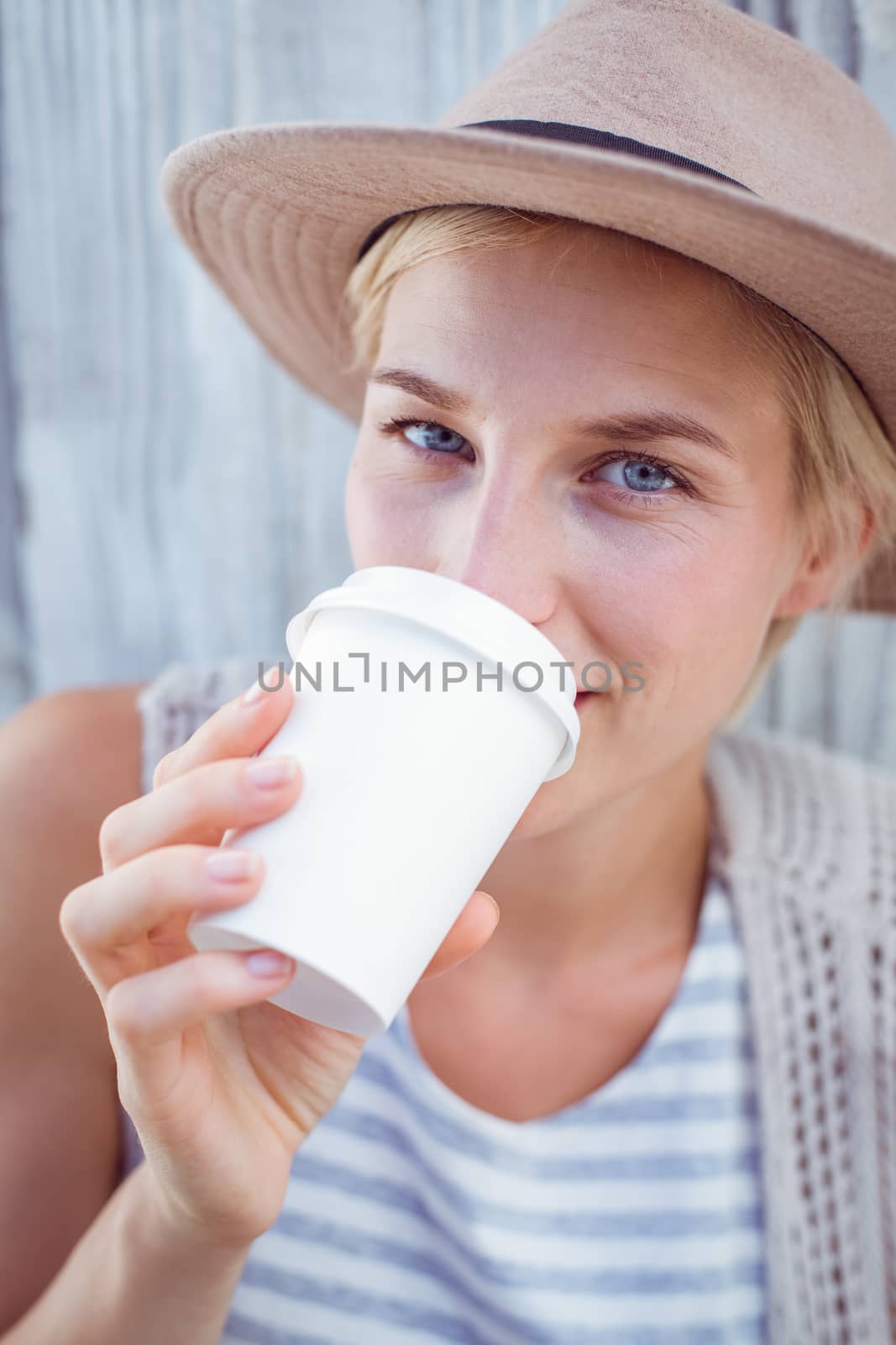 Pretty blonde woman drinking coffee on wooden background