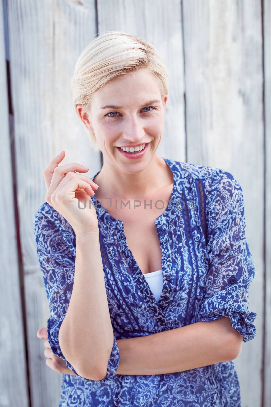 Pretty blonde woman smiling at the camera on wooden background