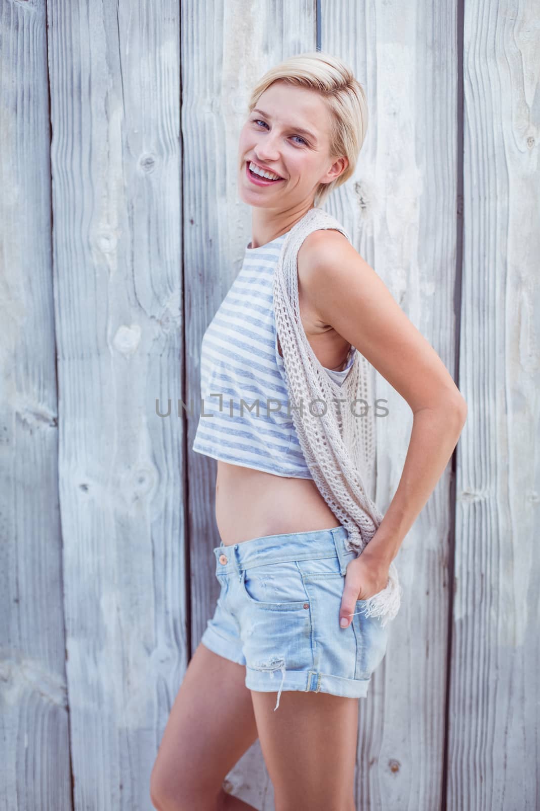 Pretty blonde woman smiling at the camera on wooden background