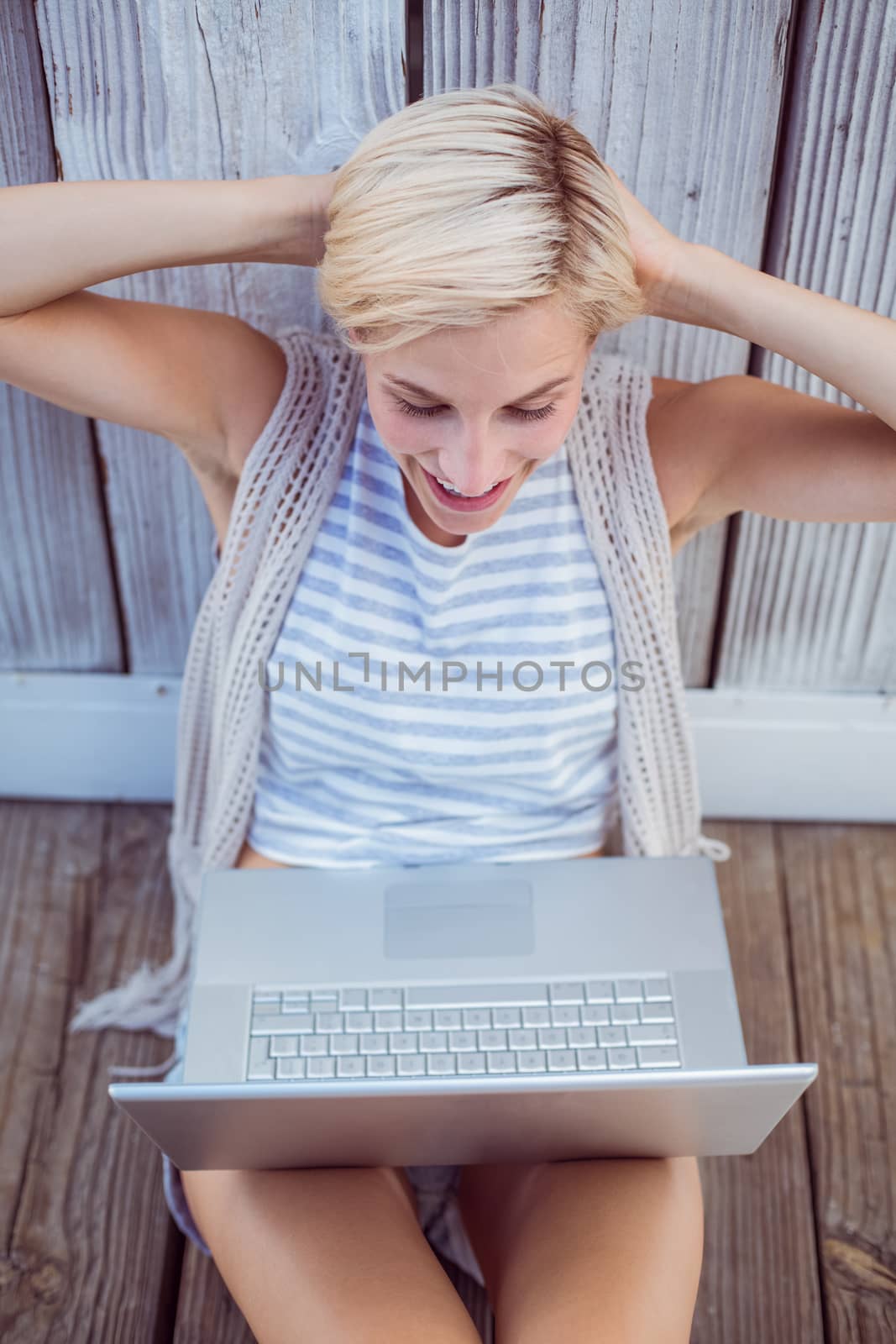 Pretty blonde woman using her laptop on wooden background