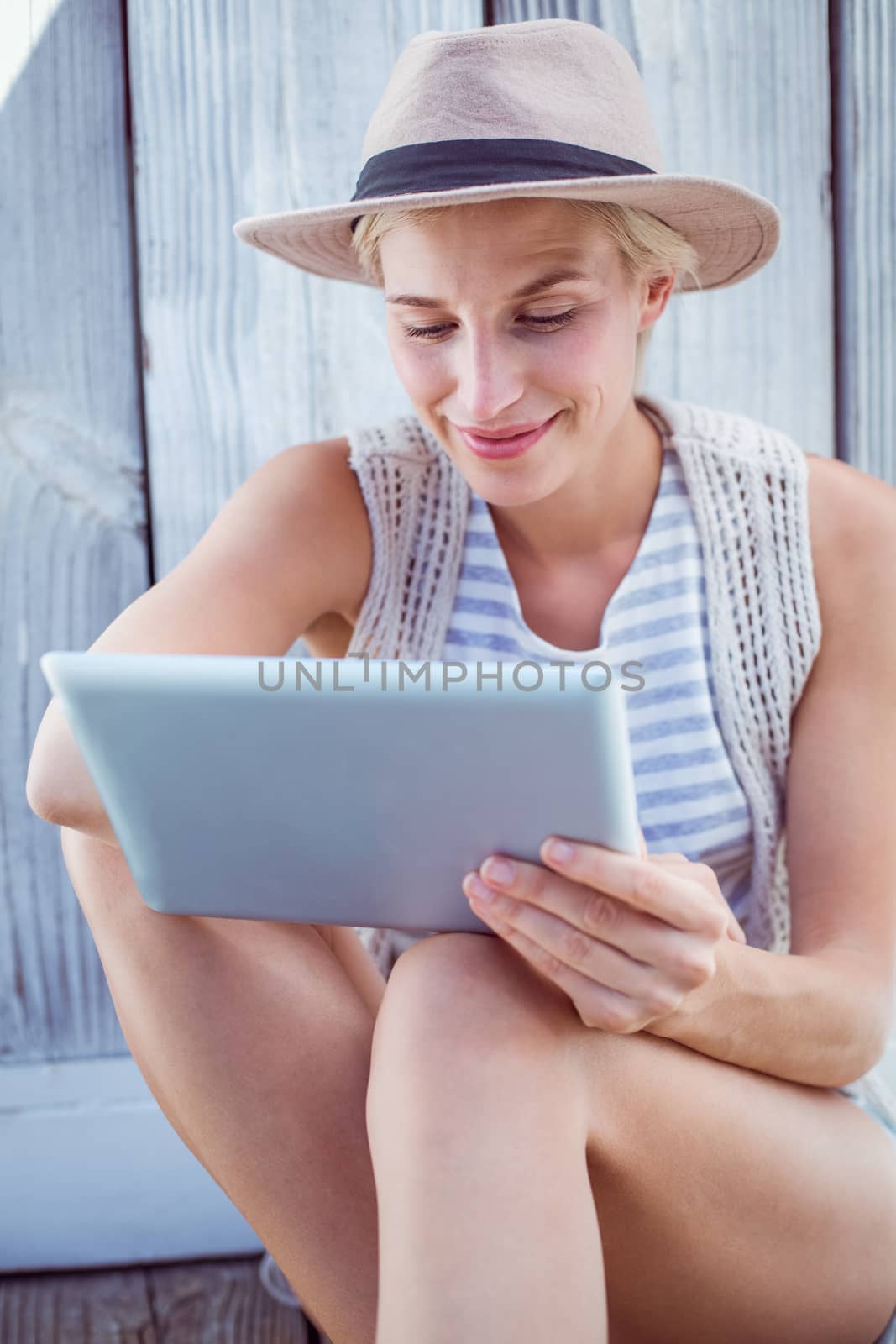 Pretty blonde woman using her tablet on wooden background