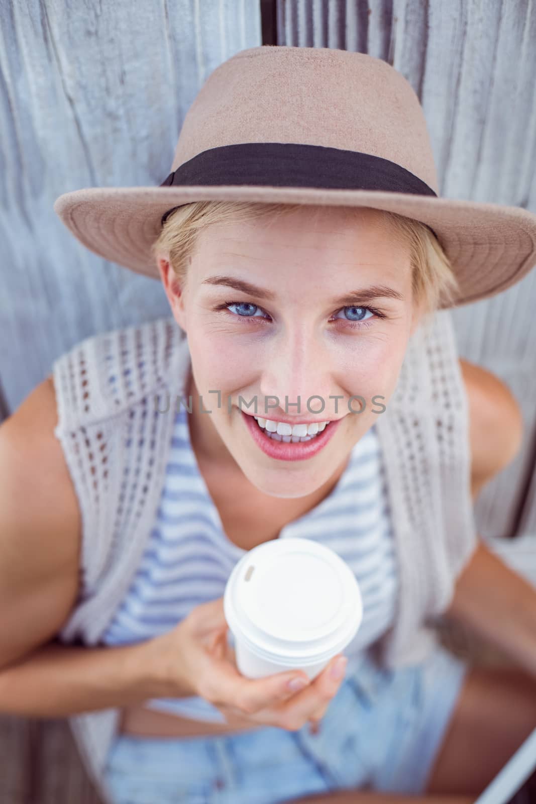 Pretty blonde woman holding goblet on wooden background