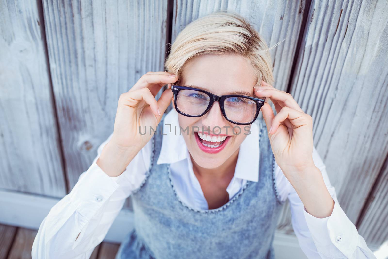 Pretty blonde woman smiling at the camera on wooden background