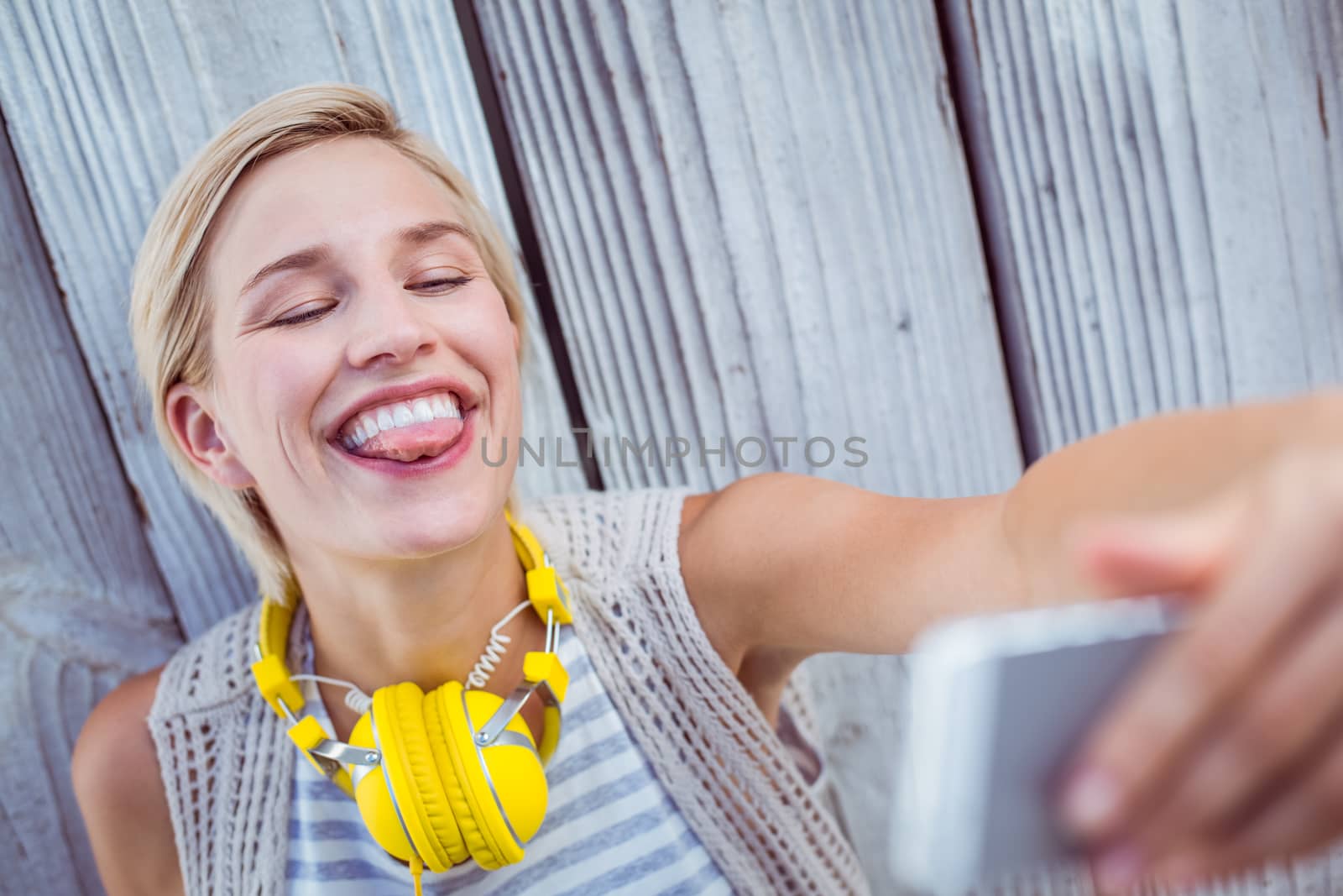 Pretty blonde woman taking selfie on wooden background