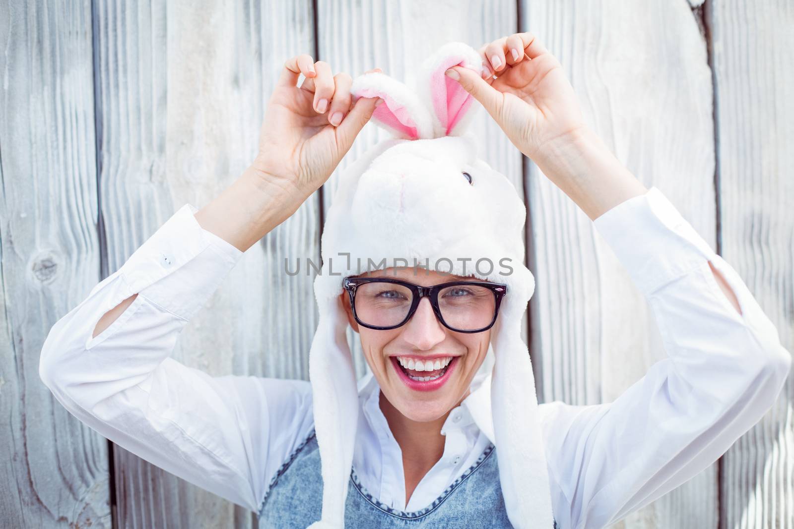 Pretty blonde woman smiling at the camera wearing funny hat on wooden background