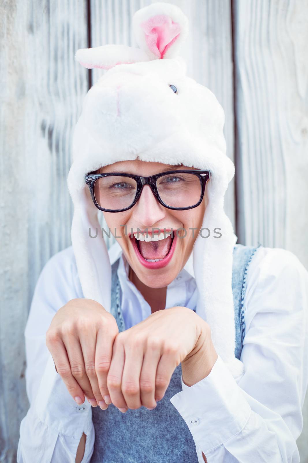 Pretty blonde woman smiling at the camera wearing funny hat on wooden background