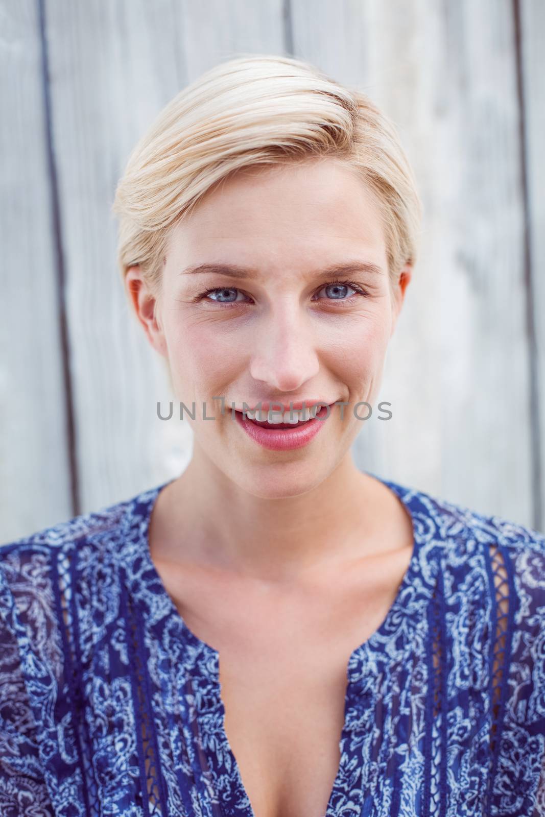 Pretty blonde woman smiling at the camera on wooden background