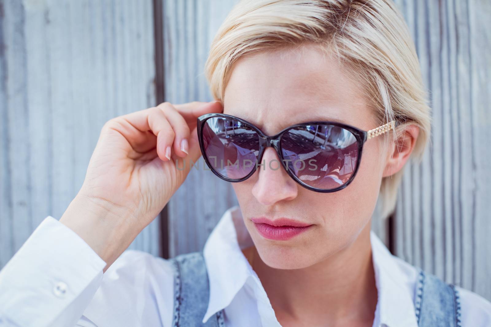 Pretty blonde woman wearing sun glasses on wooden background 