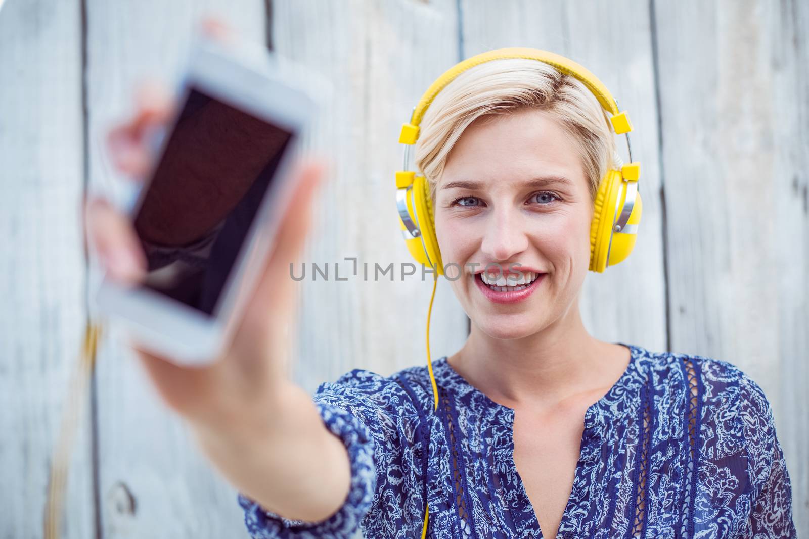 Pretty blonde woman listening music with her mobile phone  by Wavebreakmedia