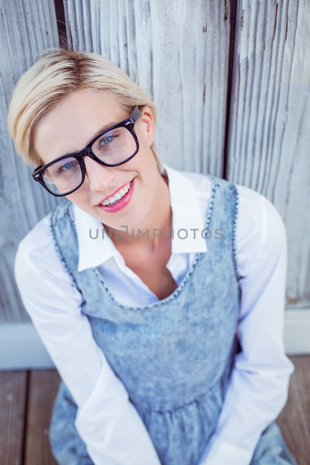 Pretty blonde woman smiling at the camera on wooden background