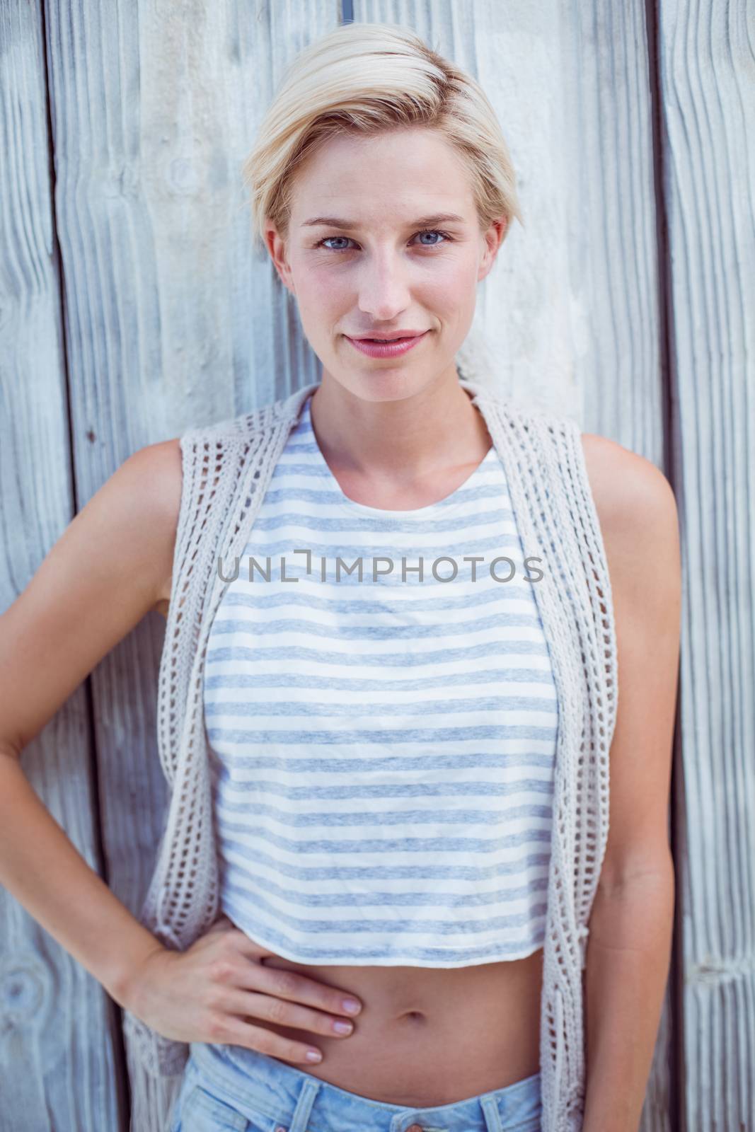 Pretty blonde woman smiling at the camera on wooden background