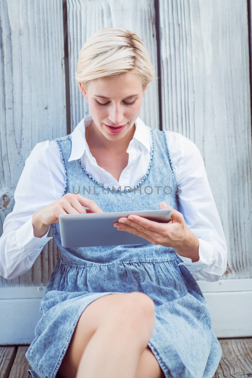 Pretty blonde woman using her tablet on wooden background