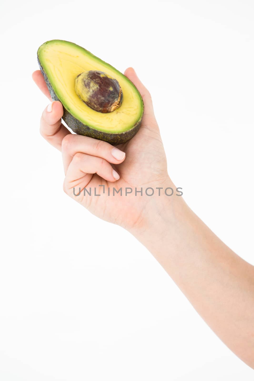 Woman holding half of an avocado on white background 