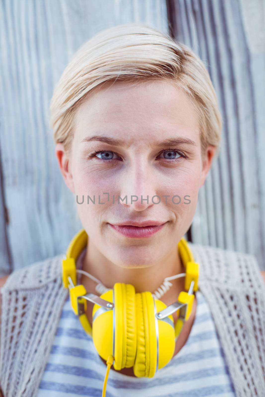 Pretty blonde woman wearing yellow headset on wooden background