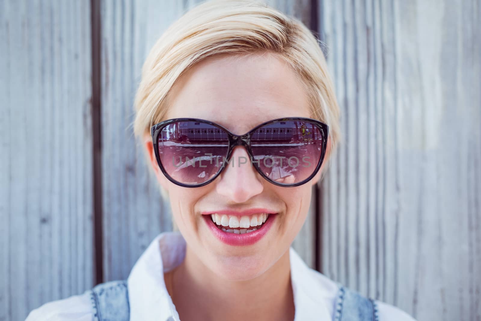 Pretty blonde woman wearing sun glasses on wooden background 