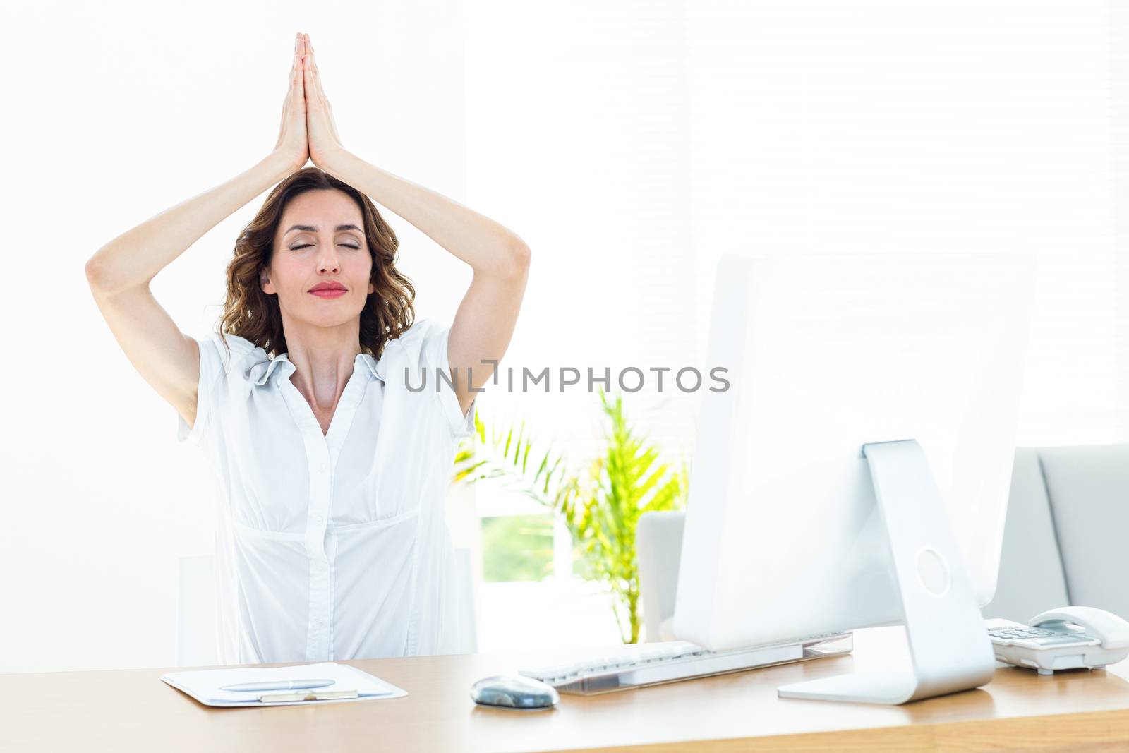 Relaxed businesswoman doing yoga on white background