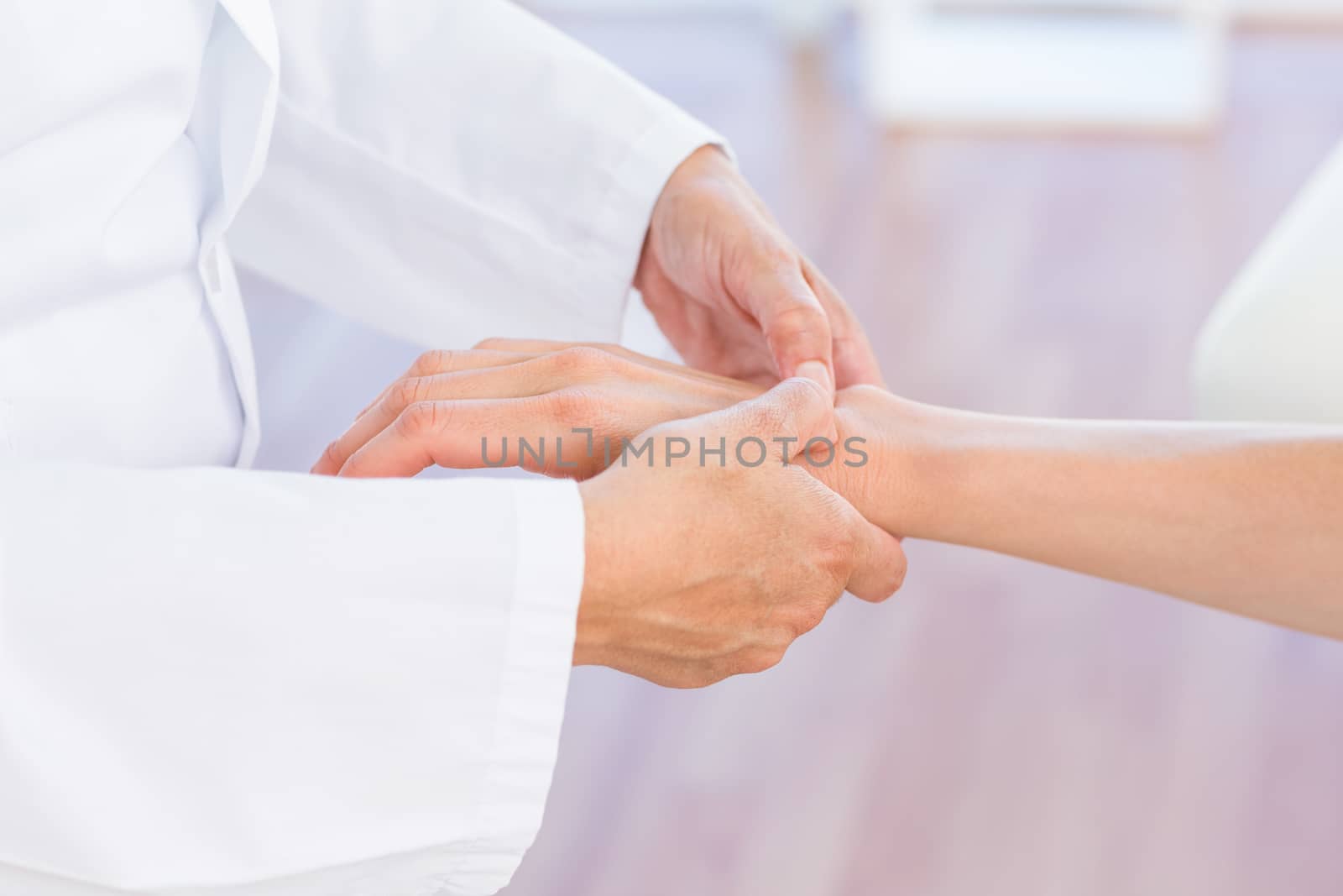 Doctor examining her patients wrist by Wavebreakmedia