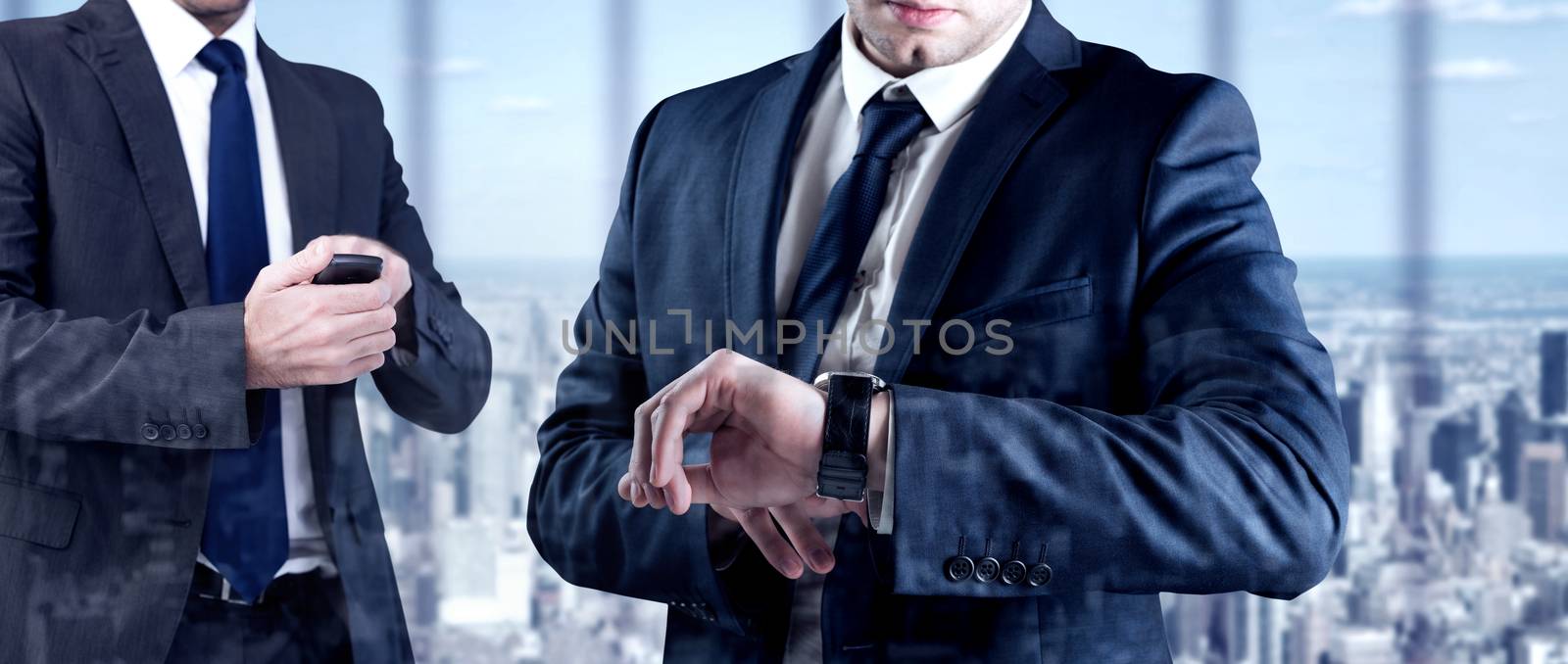 Focused businessman texting on his mobile phone against room with large window looking on city