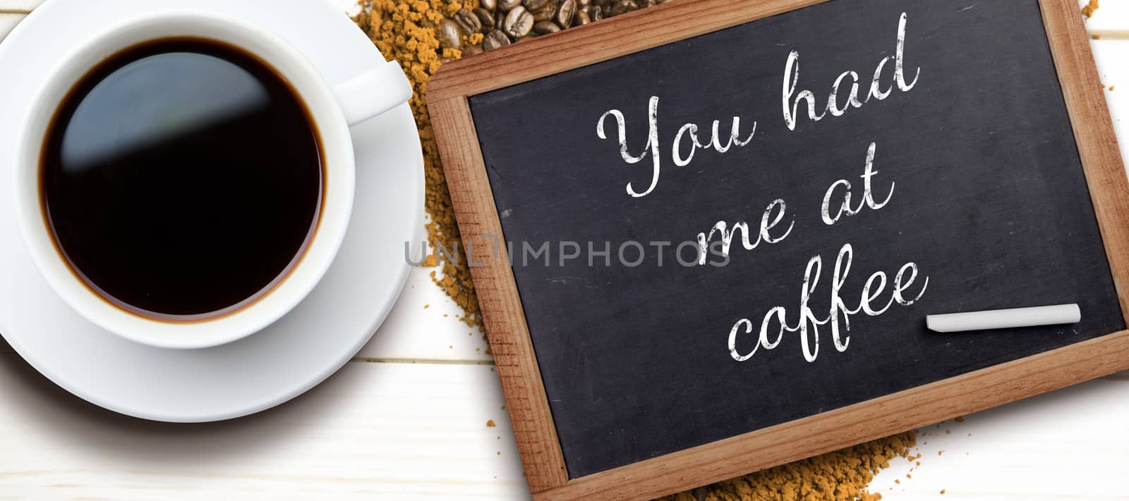 White cup of coffee against chalkboard with piece of chalk