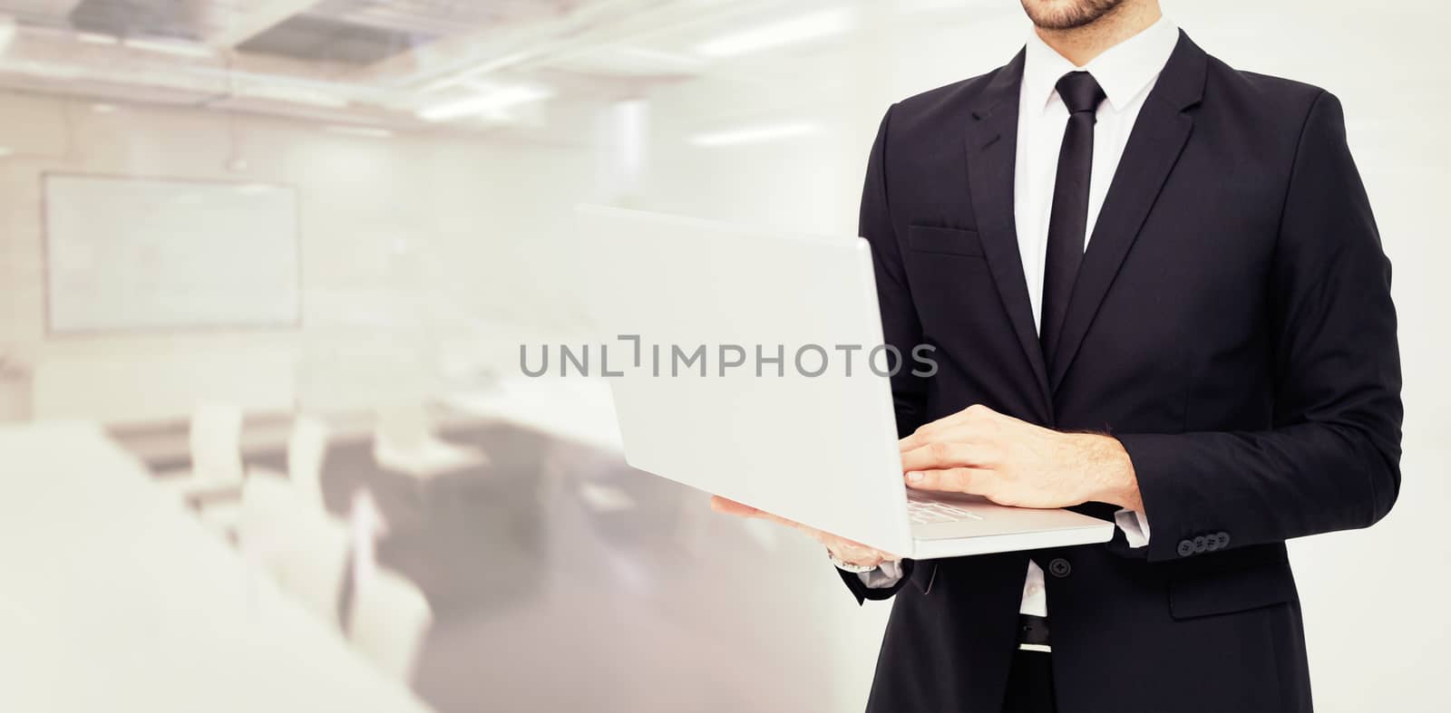 Mid section of a businessman using laptop against classroom