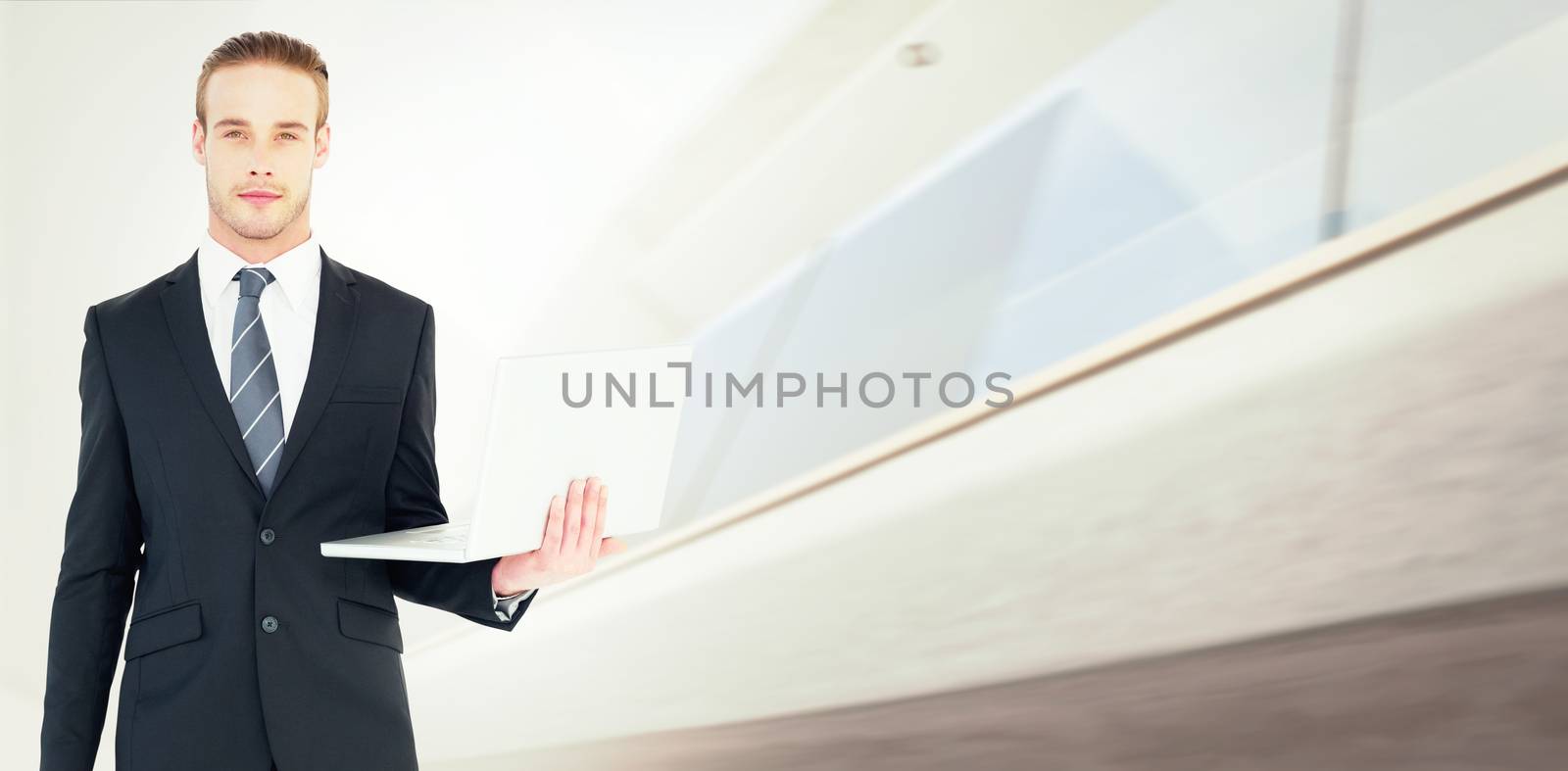 Serious businessman posing and holding laptop against modern home with large windows