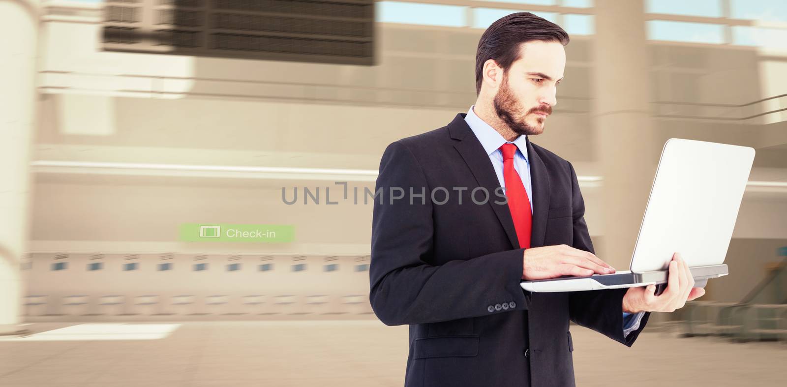 Focused businessman using his laptop against airport terminal