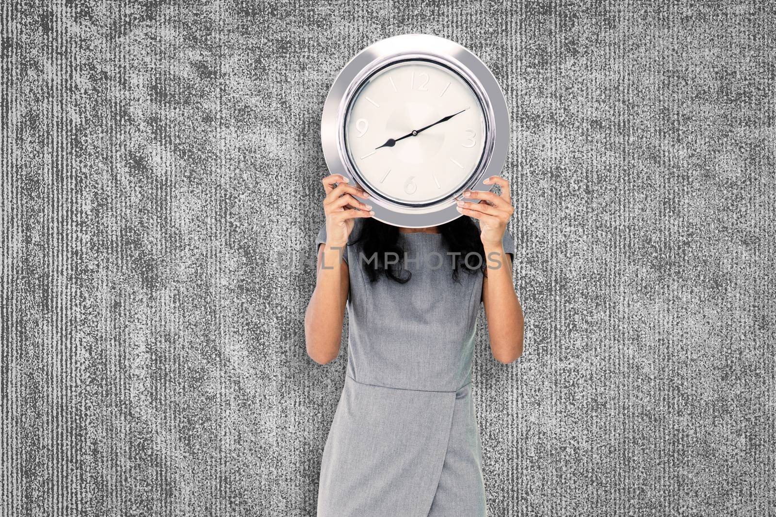 Businesswoman holding clock against grey background