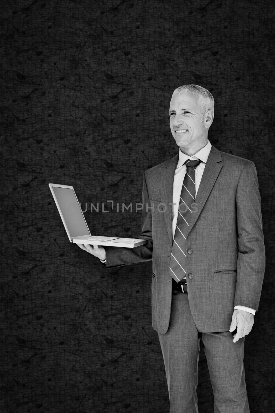 Businessman using laptop against grey background