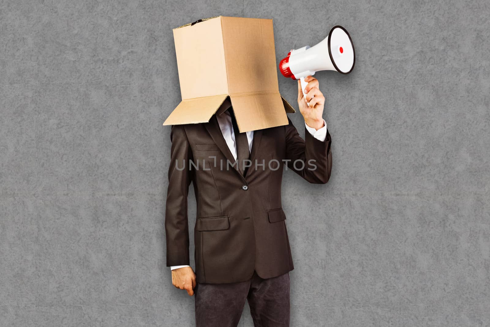 Anonymous businessman holding a megaphone against grey background