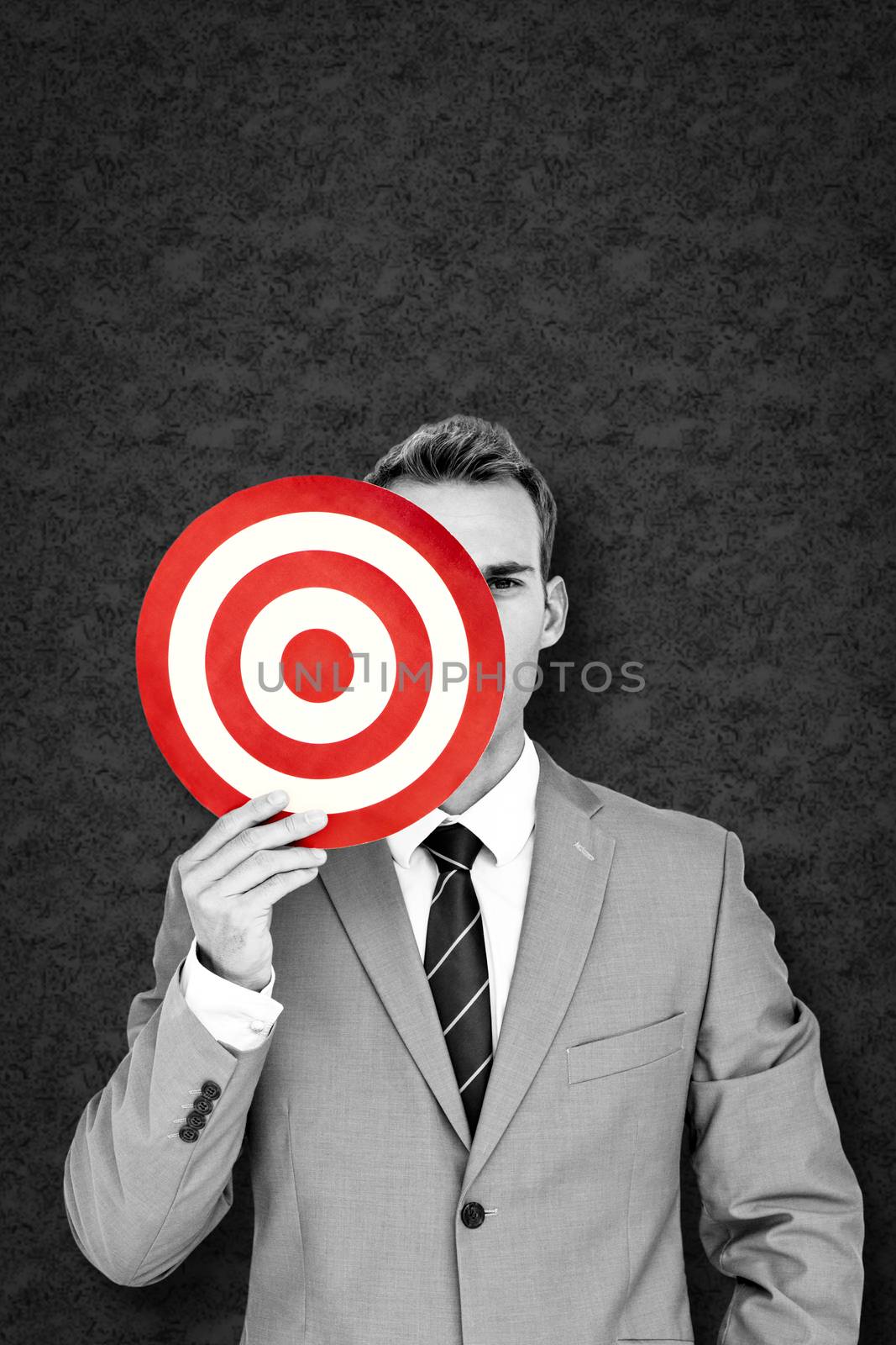 Businessman holding target against grey background