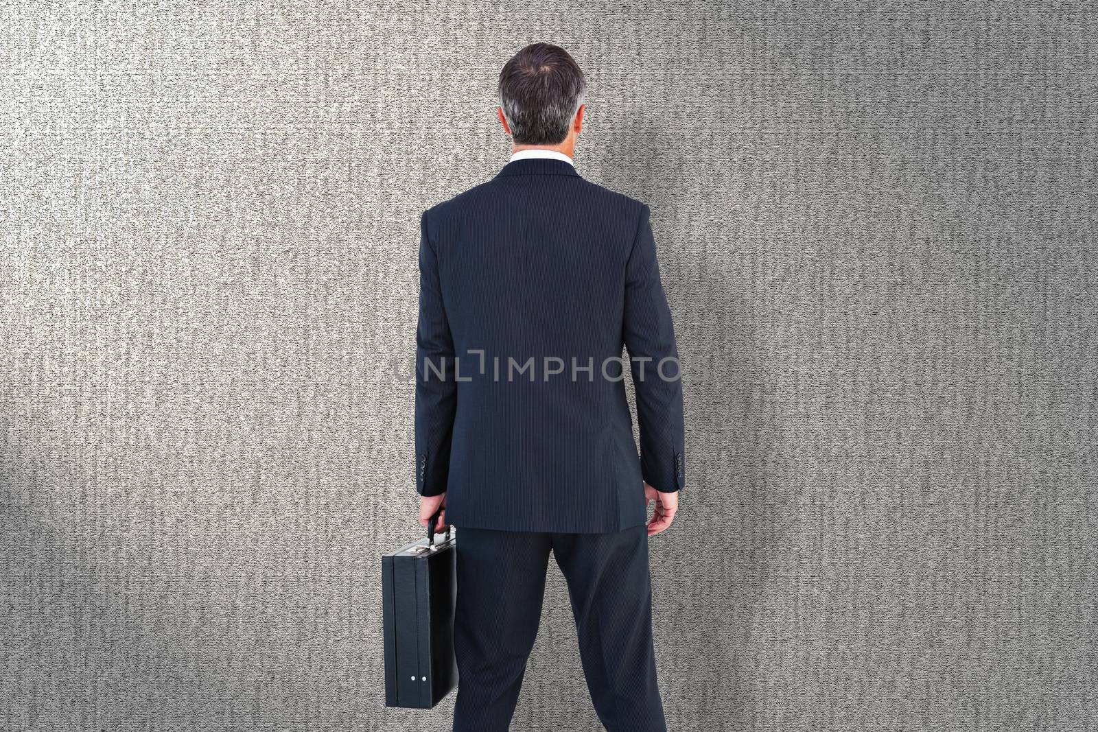 Businessman in suit holding a briefcase against grey background