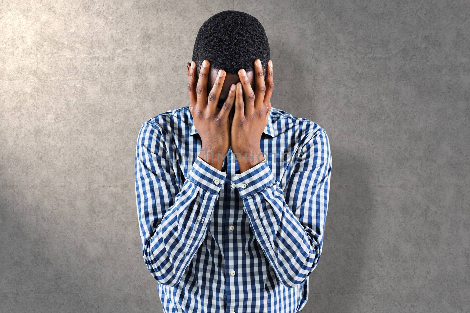 Young businessman with head in hands against grey background