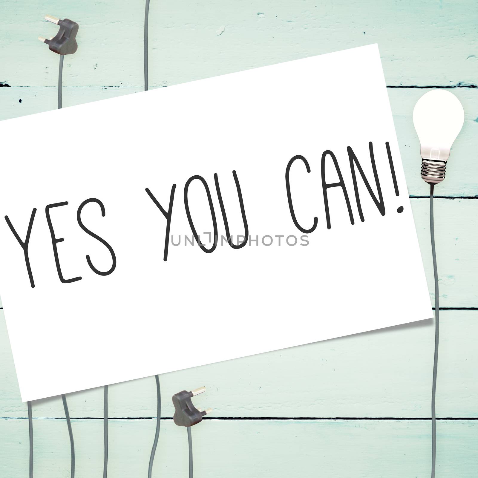 The word yes you can! and white card against light bulbs on wooden background