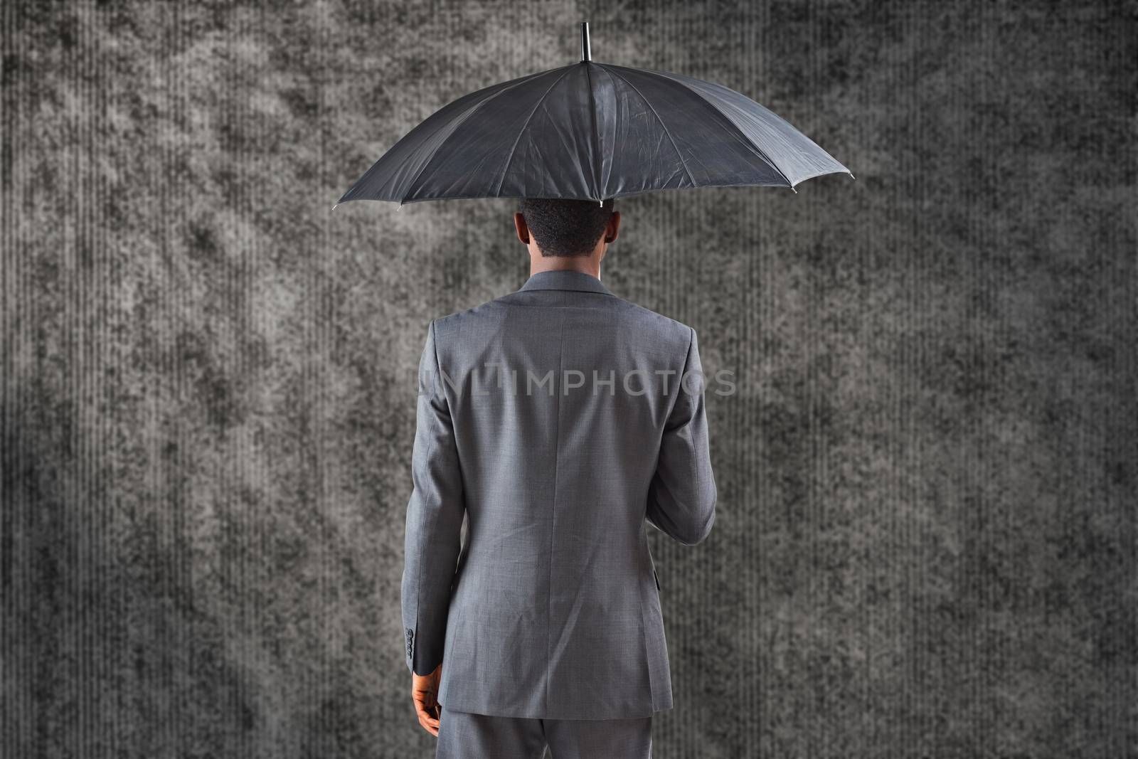 Businessman standing under umbrella against grey background
