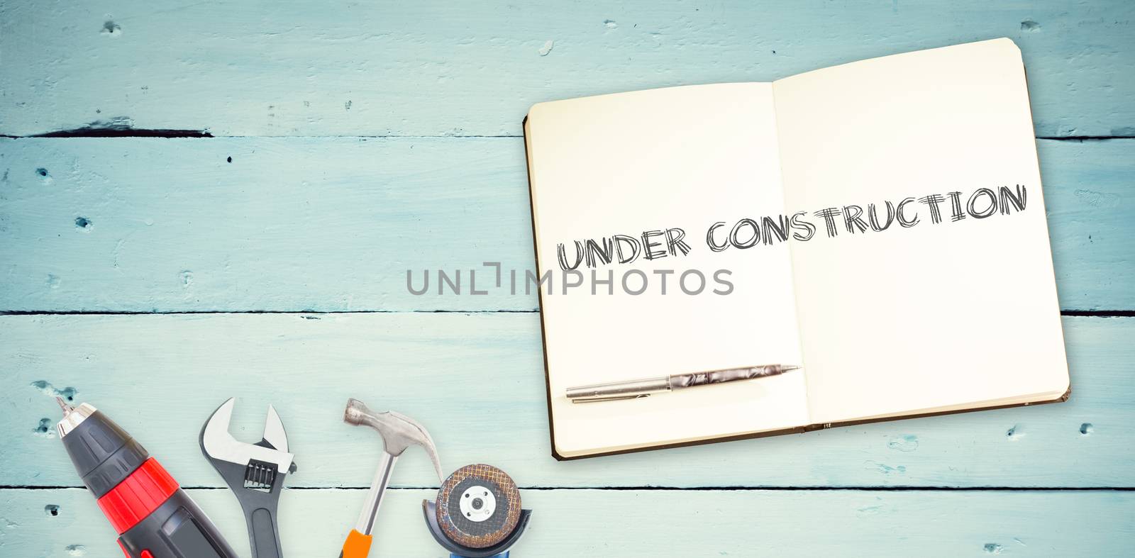 The word under construction against tools and notepad on wooden background