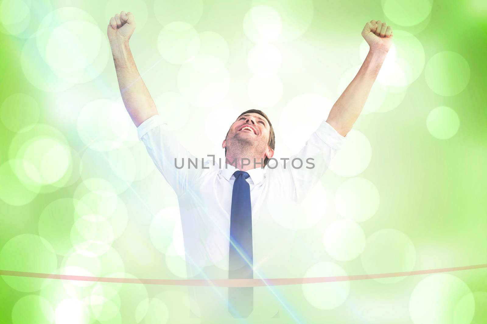 Businessman crossing the finish line against green abstract light spot design