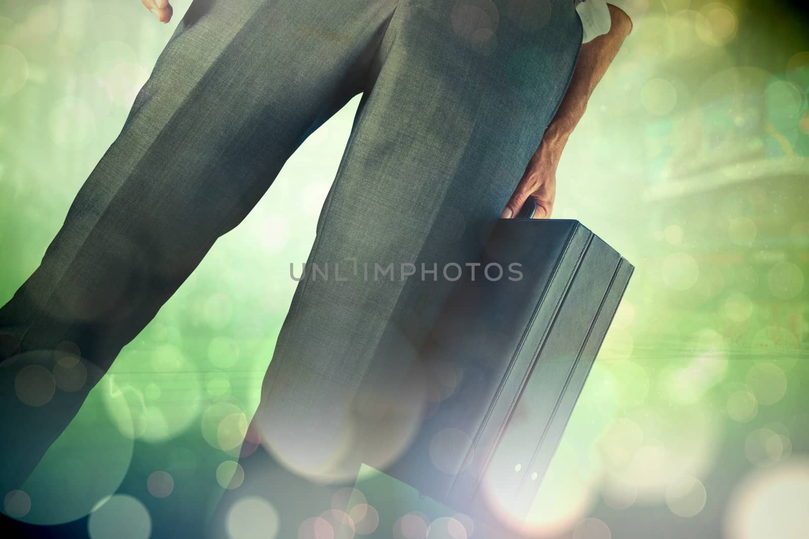 Businessman holding briefcase against green abstract light spot design