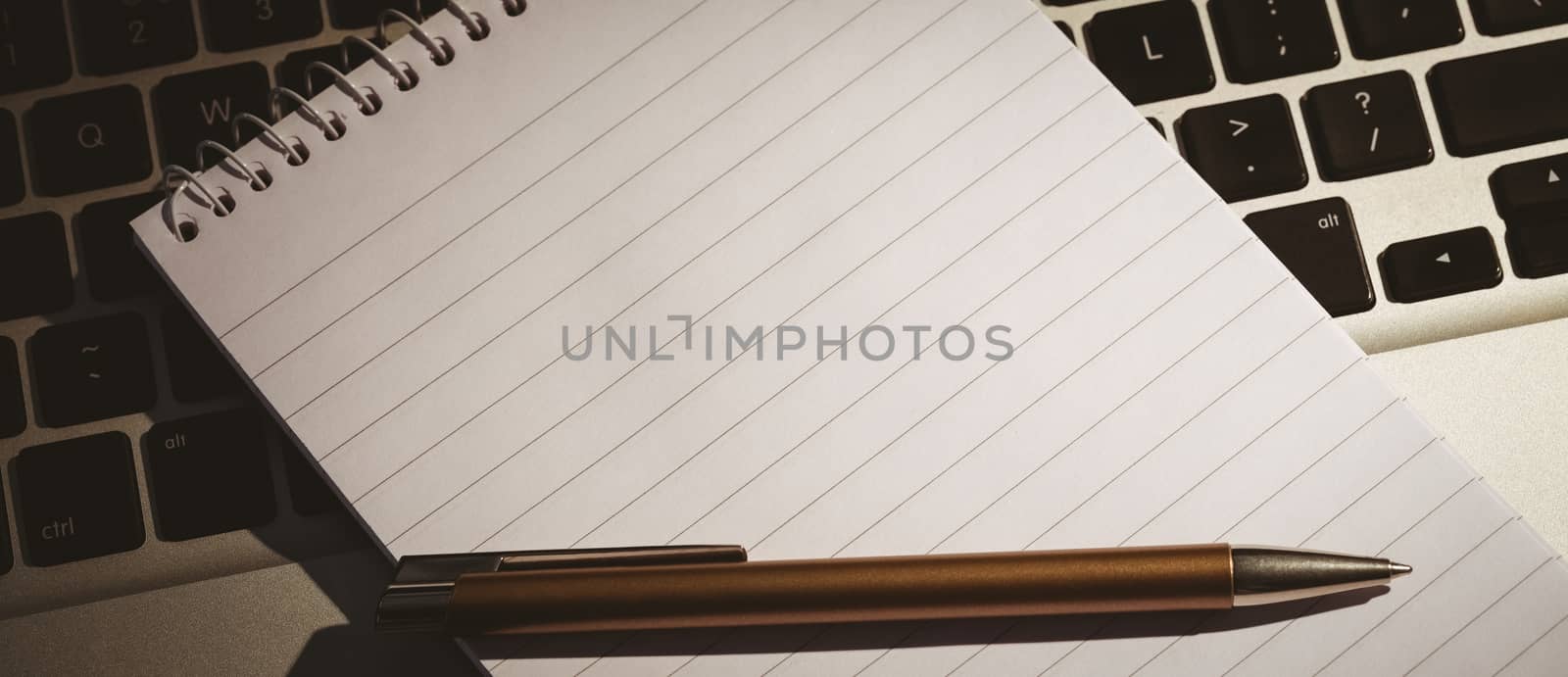 Notepad and pen on laptop by Wavebreakmedia