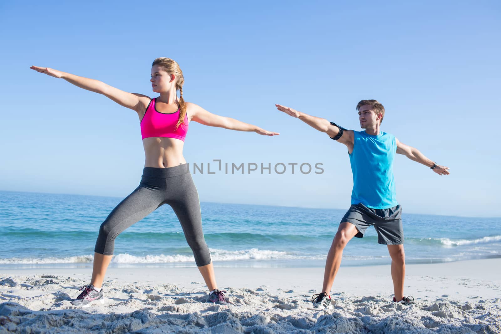 Happy couple doing yoga beside the water by Wavebreakmedia