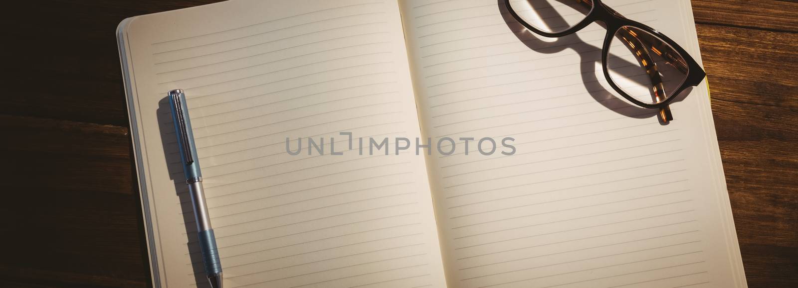 Empty notepad with reading glasses on a desk