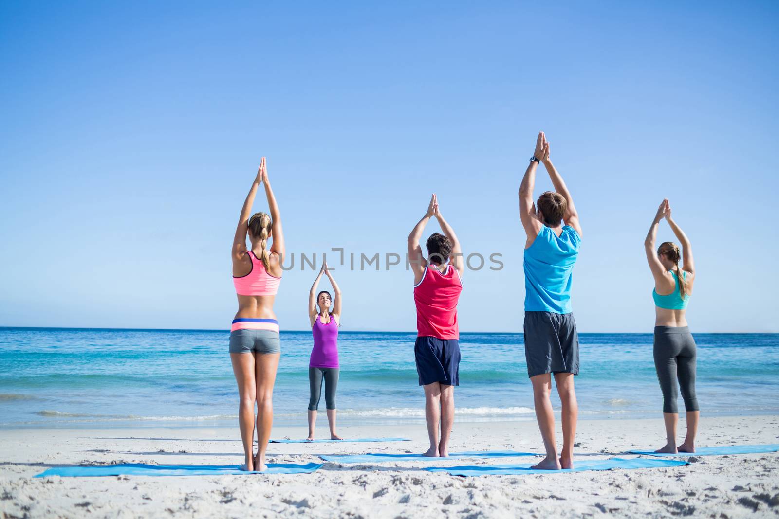 Friends doing yoga together with their teacher  by Wavebreakmedia