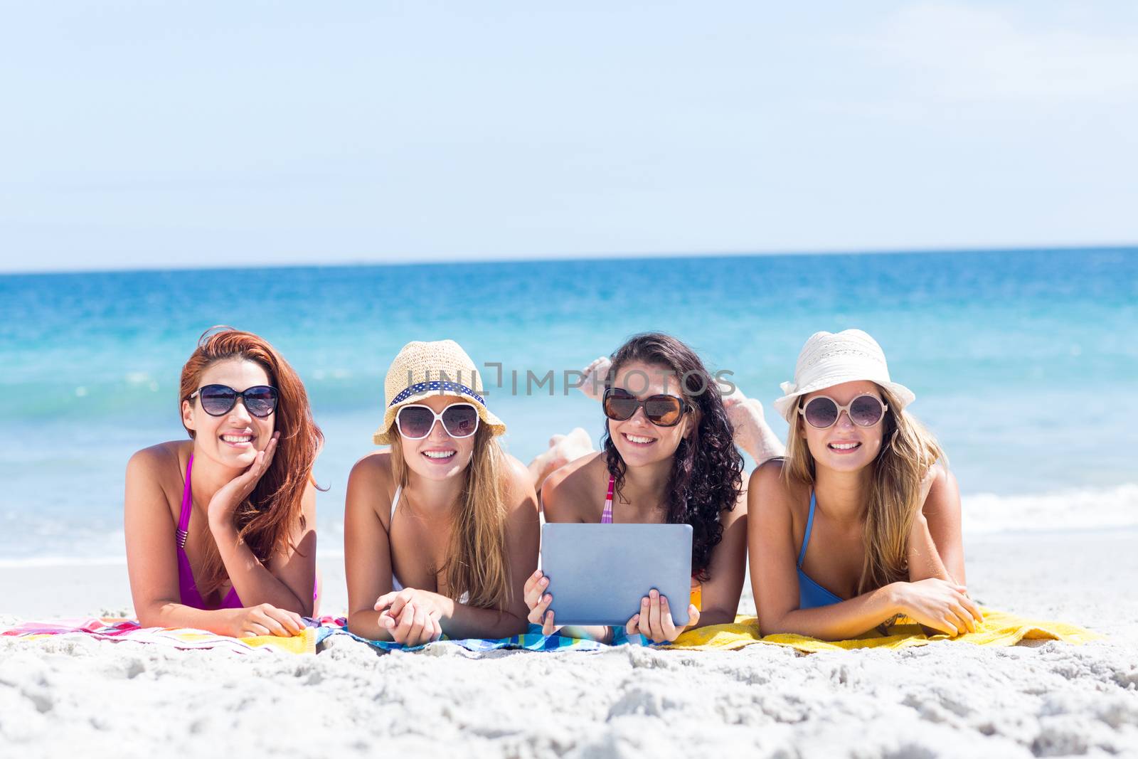 Happy friends wearing sun glasses and using tablet by Wavebreakmedia