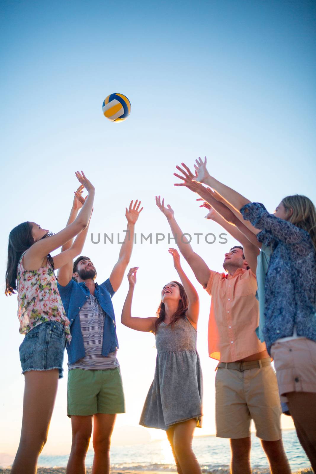 Happy friends throwing volleyball at the beach